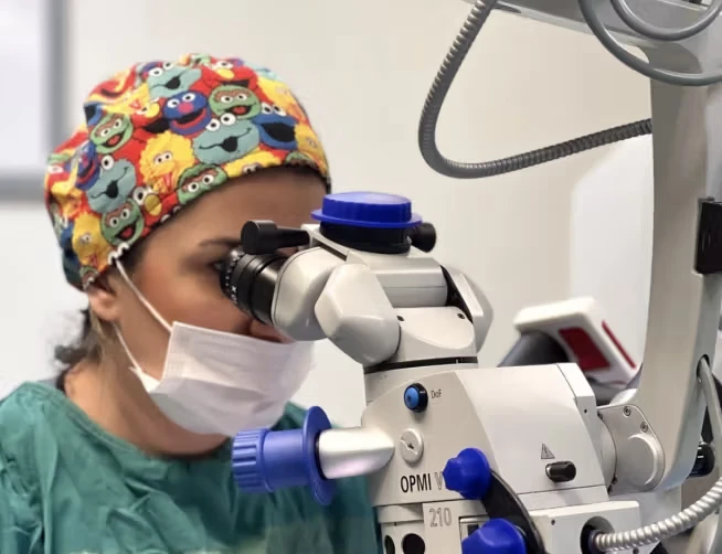 Doctor with playful hat looking in microscope