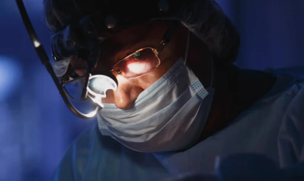 Surgeon operating in dark room, wearing headlight